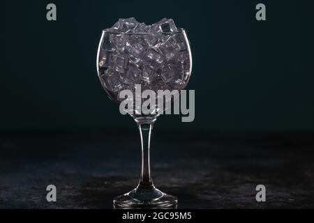 Glass full of ice standing on a table in the dark Stock Photo