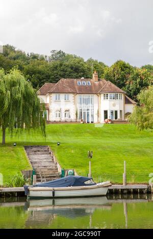 House on the river Thames at Goring on Thames Oxfordshire with a boat moored at the bottom of the garden Stock Photo