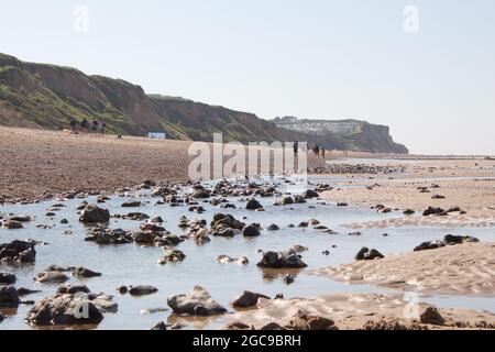 Long strech of sand on the shore of Cromer, Nortfolk in England, beautiful seascape with rocks reflecting on beach ponds water in a sunny day Stock Photo