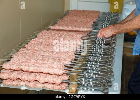 Raw sausages strung on skewers before grilling Stock Photo