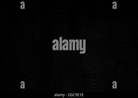 Front view of plastered wall texture background in black and white. Dark, almost black, high resolution full frame textured background. Stock Photo