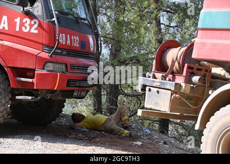 07 August 2021, Turkey, Köycegiz: A firefighter sleeps on the ground between emergency vehicles in forests in the municipality of Mugla in western Turkey. Ten days ago, fires broke out in numerous provinces of Turkey. Vast areas of forest, fields and villages have since gone up in flames. Photo: Anne Pollmann/dpa Stock Photo