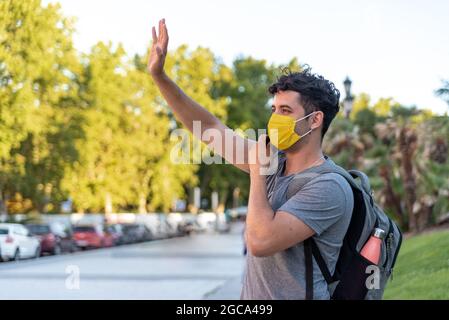 Young latin man with face mask using phone Stock Photo