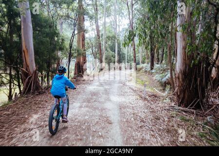 A child cycles at speed in Mt Evelyn on the popular Lilydale to Warburton Rail Trail on a warm autumn day in Victoria, Australia Stock Photo