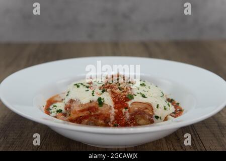 Hearty bowl of cheesy lasagna servved as authentic Italian meal to fill the appetite. Stock Photo