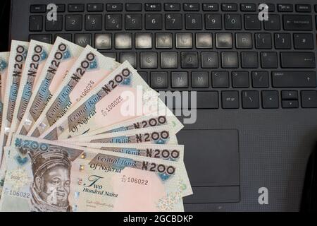 Multiple naira notes, cash or nigerian currency spread neatly on a laptop's key board Stock Photo