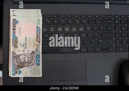 Multiple naira notes, cash or nigerian currency spread neatly on a laptop's key board Stock Photo