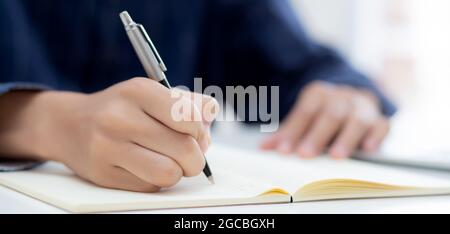 Closeup hand of man writing on notebook with pen on desk, freelance is author, businessman write on notepad on table, book, letter and report, finance Stock Photo