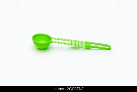 Green measuring plastic spoon on isolated white background Stock Photo