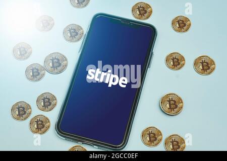 Tashkent, Uzbekistan - April 2, 2021: Stripe logo on mobile phone screen and pile of bitcoins cryptocurrency. Symbol of cryptocurrency rolling out in Stock Photo