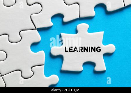 The word learning on a puzzle piece with blue background. Education concept. Stock Photo