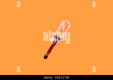 Shaving foam gel and razor on orange background. A multiple use shaving razor and cream. View from above Stock Photo