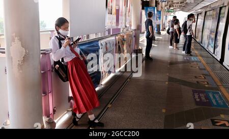 Asian Female Student in Red and White School Uniform Waiting for a Train Saphan Taksin BTS Skytrain Station Chao Phraya River Bridge Bangkok Thailand Stock Photo