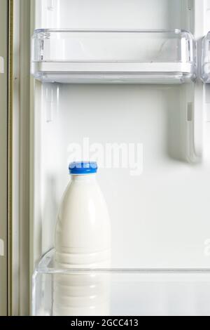 A bottle of sour cream in refrigerator. Yogurt in white bottle on shelf of open empty fridge. Weight loss diet concept. Fermented food Stock Photo