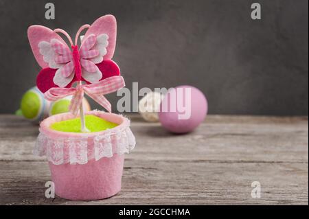 Colorful pink butterfly closeup, green easter eggs on wooden background Stock Photo