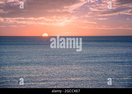 Sun Setting On Horizon At Sunset or Sunrise Over Sea Or Ocean Stock Photo