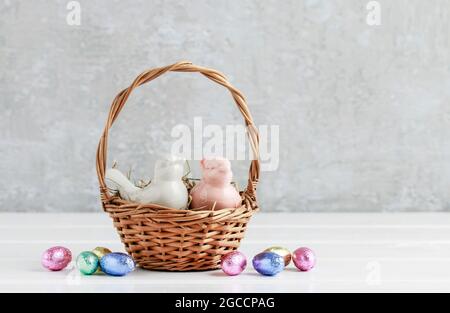 Two ceramic birds in wicker Easter basket. Eggs around, grey stone background. Festive decor Stock Photo