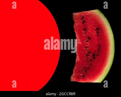 In the photo, a piece of ripe watermelon on a black background and a place for the text, highlighted in red Stock Photo