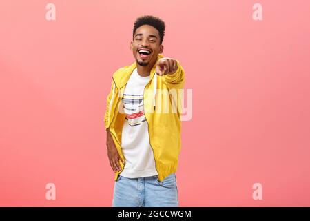 ha-ha loser. Portrait of happy amused energetic african american bearded male in yellow trendy jacket pointing at camera with index finger and Stock Photo