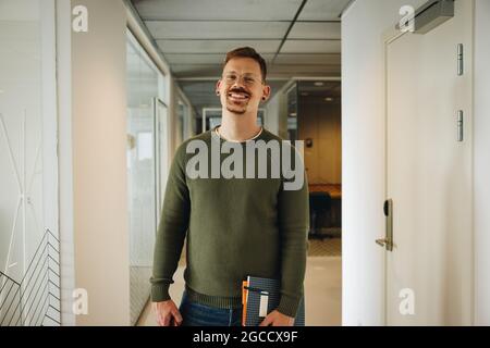 Positive male executive in office. Portrait of a businessman in office corridor. Stock Photo