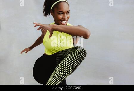 Female athlete in sportswear doing fitness workout. African woman doing stretching exercise and smiling. Stock Photo