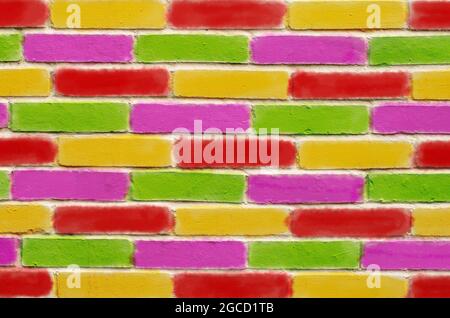 Brick wall, with green purple red and yellow painted bricks Stock Photo