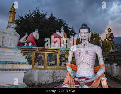 buddha skeleton statue sitting in meditation posture with giant buddha at background at evening image is taken at giant buddha statue tawang arunachal Stock Photo