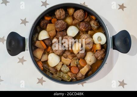 Casserole of a stew of meat balls with vegetables on a white background with stars. Typical dish of the Mediterranean diet, prepared on the island of Stock Photo