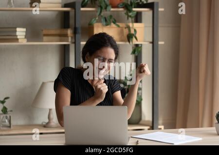 Close up overjoyed businesswoman in glasses celebrating success, using laptop Stock Photo