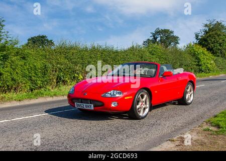2002 red Jaguar XK8 sports cabrio, 2dr 4196 cc petrol en-route to Capesthorne Hall classic July car show, Cheshire, UK Stock Photo