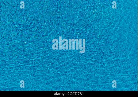 The crystal clear water of a swimming pool is moved by the wind creating beautiful reflections Stock Photo
