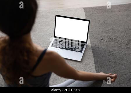 Top view woman practicing yoga online, laptop with empty screen Stock Photo