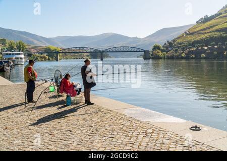 PINHAO, DOURO REGION, PORTUGAL - OCTOBER 22, 2017: People fishing on a riverside  on Duoro river in Pinhao village, Portugal Stock Photo