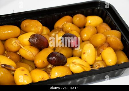 Closeup Image Of Red And Yellow Dates Fruit In Black Container. White Background And Selective Focus Stock Photo