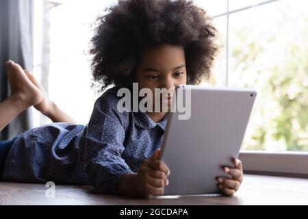 Little teen biracial girl child use tablet Stock Photo