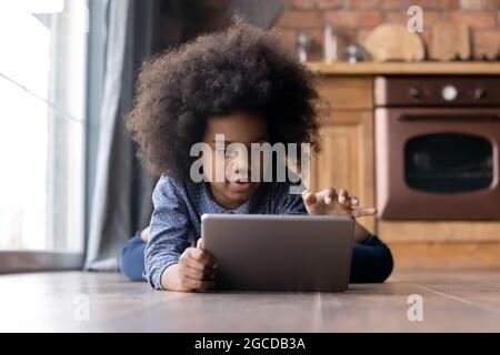 Small teen ethnic girl child play on tablet Stock Photo
