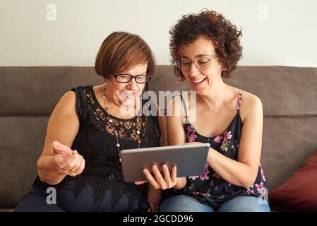 Senior woman is happy to learn how to use social networks while young daughter explains how to use the tablet Stock Photo