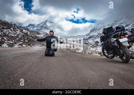 girl solo traveler at isolated tarmac road with snow cap mountains in background at morning image is taken at sela pass tawang arunachal pradesh india Stock Photo