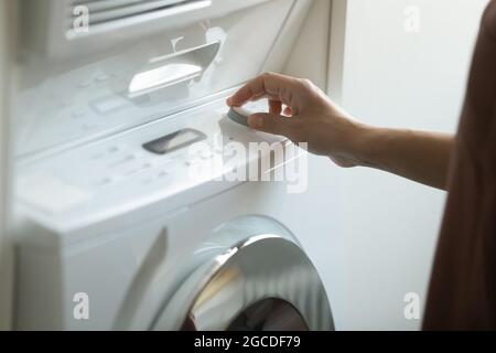 Close up of woman turn on modern washing machine Stock Photo