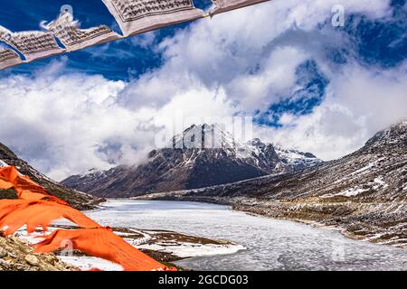 snow cap mountain with dramatic sky through the blurred buddhism flags frame at day image is taken at sela pass tawang arunachal pradesh india. Stock Photo