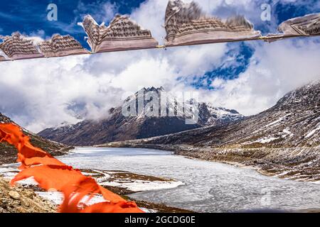 snow cap mountain with dramatic sky through the blurred buddhism flags frame at day image is taken at sela pass tawang arunachal pradesh india. Stock Photo