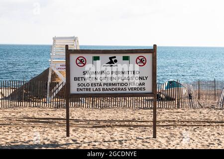 Swimming permitted between green flags only on a beach with a life guard stand and the long Islnad Sound in the background. Stock Photo