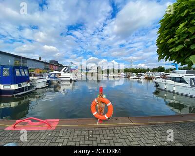 Oberhausen (Centro), Germany - July 9. 2021: View on inland port with boats in summer with orange lifebelt, sealife building background Stock Photo