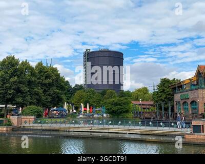 Oberhausen (Centro), Germany - July 9. 2021: View over water canal beyond beach on gasometer tower against summer sky Stock Photo