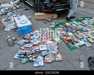 Exeter, UK - August 2021: A young caucasian man selling a large number of DVDs, CDs, video-games and other items at a car boot sale in the UK Stock Photo