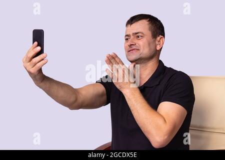 Deaf adult man using hearing aid to communicate freely with relatives on a video call and feel himself joyful. Stock Photo