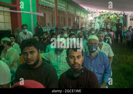 Bangladeshi people wearing face masks wait to receive a dose of Moderna Covid-19 vaccine during a vaccination campaign at a vaccination center in Dhaka. According to the Bangladesh Directorate General of Health Services (DGHS) the nationwide mass vaccination program starts of its vaccination drive aiming at injecting 3.5 million people in six days. Bangladesh has recorded nearly 1.31 million coronavirus infections and 21,638 fatalities since the pandemic begun. Stock Photo