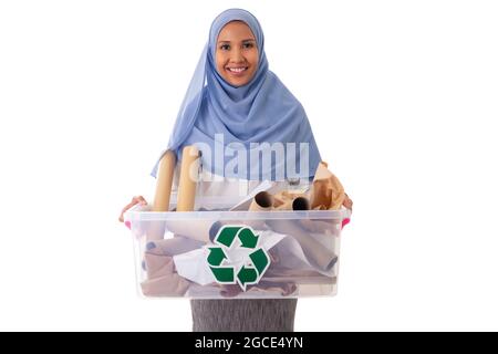 eco living and environment concept - happy smiling young asian muslim woman in hijab holding paper garbage in plastic box isolated over white Stock Photo