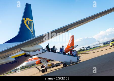 Passengers disembark from Ryanair flight as Easyjet aircraft prepares for takeoff at Bristol Airport, England, UK Stock Photo