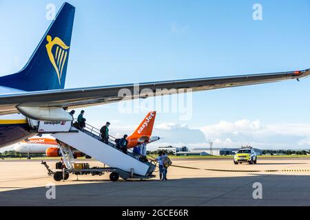 Passengers disembark from Ryanair flight as Easyjet aircraft prepares for takeoff at Bristol Airport, England, UK Stock Photo